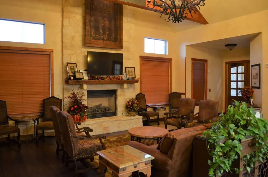 The waiting room, with a stone fireplace, armchairs and a television.